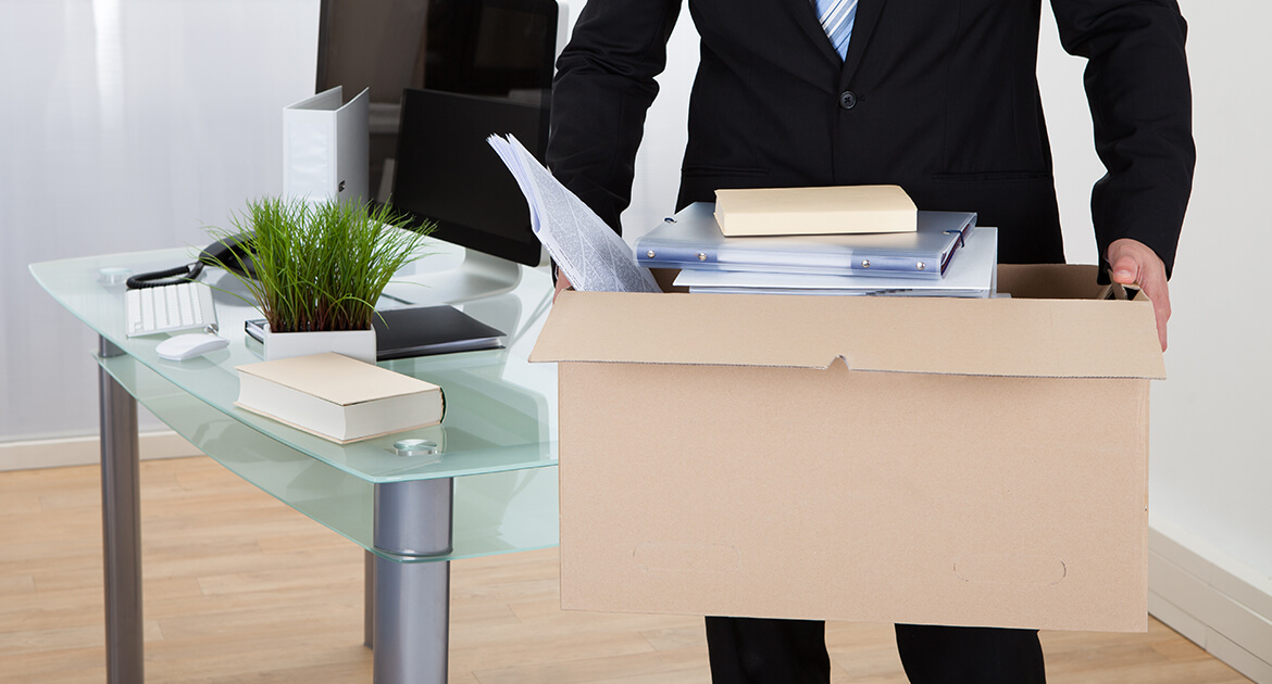 Fired employee carrying a box of his belongings away from the office