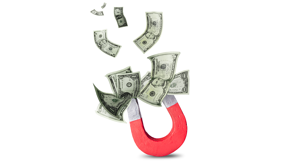 Horseshoe magnet attracting numerous $1 and $5 bills