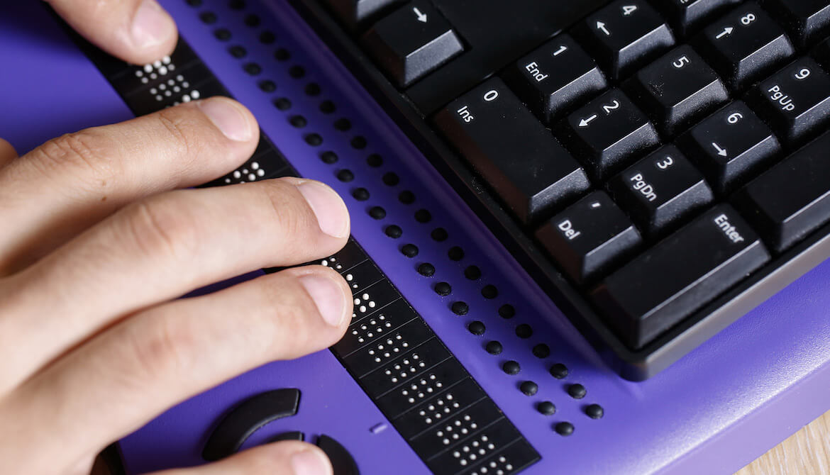 Blind person using computer with braille computer display and a computer keyboard