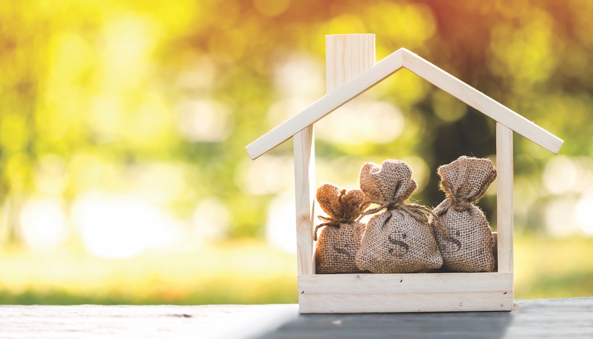 wooden house cut out with three bags of money inside