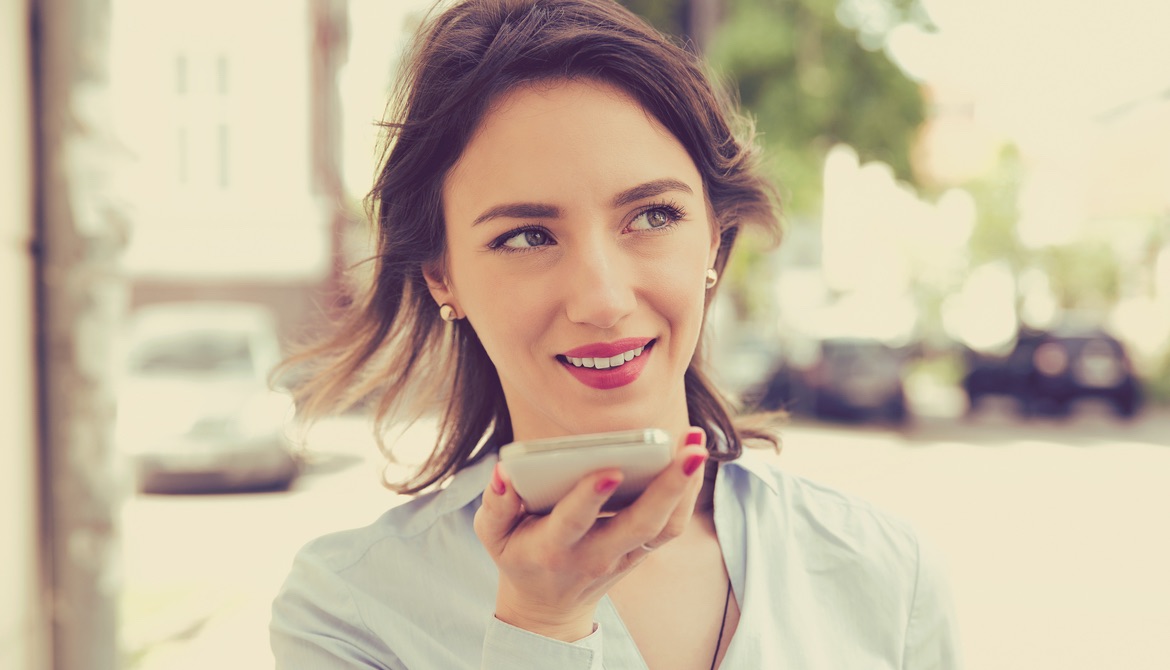 woman using voice assistant on smartphone outdoors