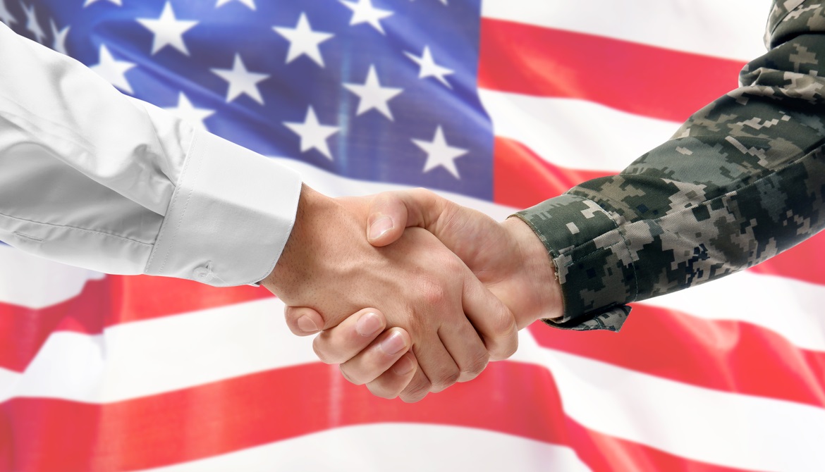 civilian and military arms shake hands in front of a U.S. flag