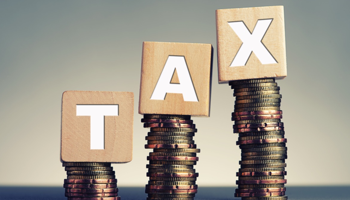 tax spelled out in wooden blocks on stacks of coins