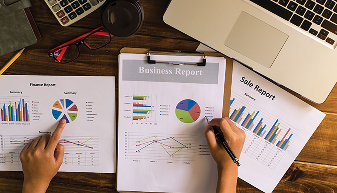 Person reviewing business reports with graphs and charts at a desk