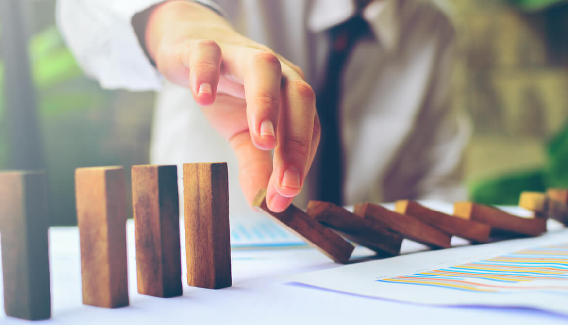 Business person stopping a line of falling dominos