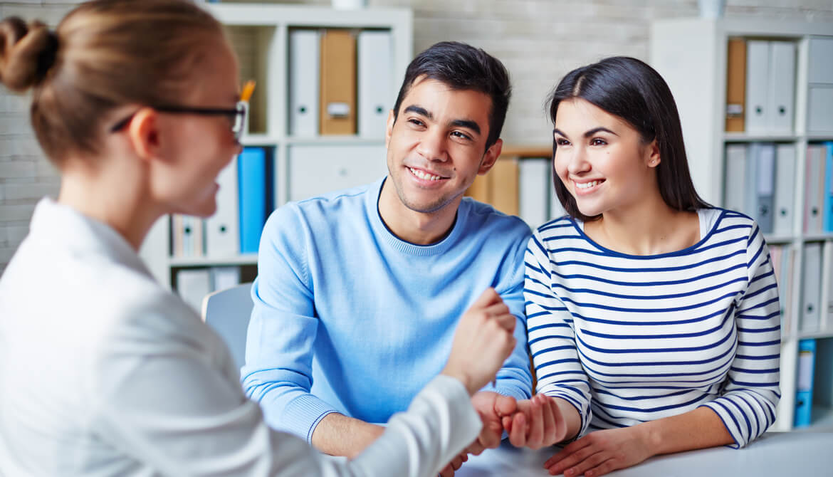 Happy young couple making deal with an agent