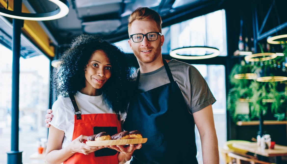 two young male and female bakery owners with baked goods