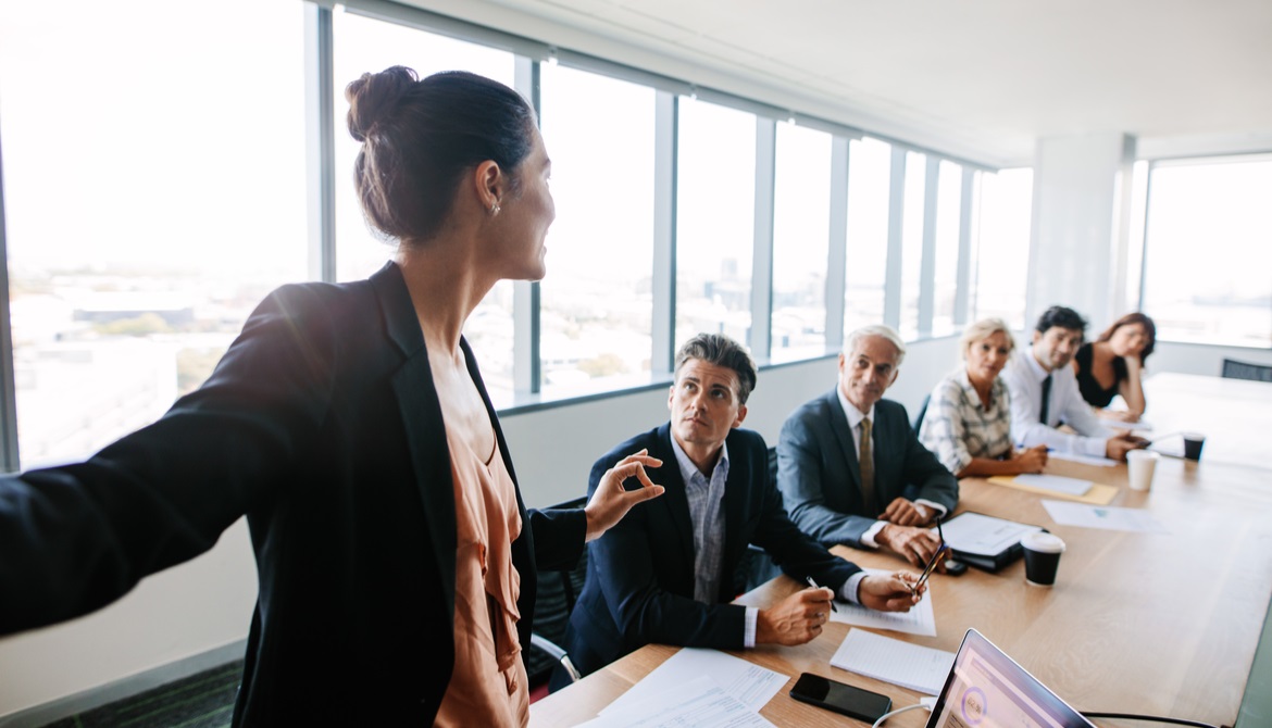 female asian executive presenting to a group around a board room table