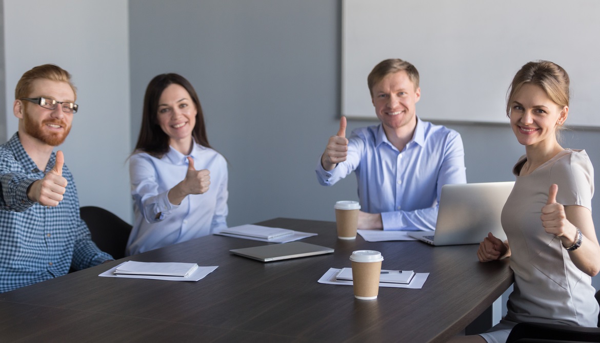 young executives around a table giving thumbs up