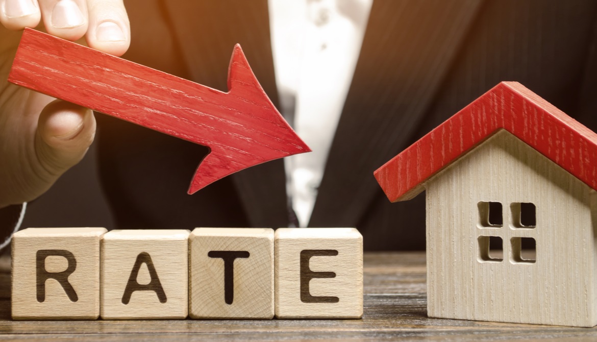 man holding arrow pointing down toward a house over the word rates in wooden blocks