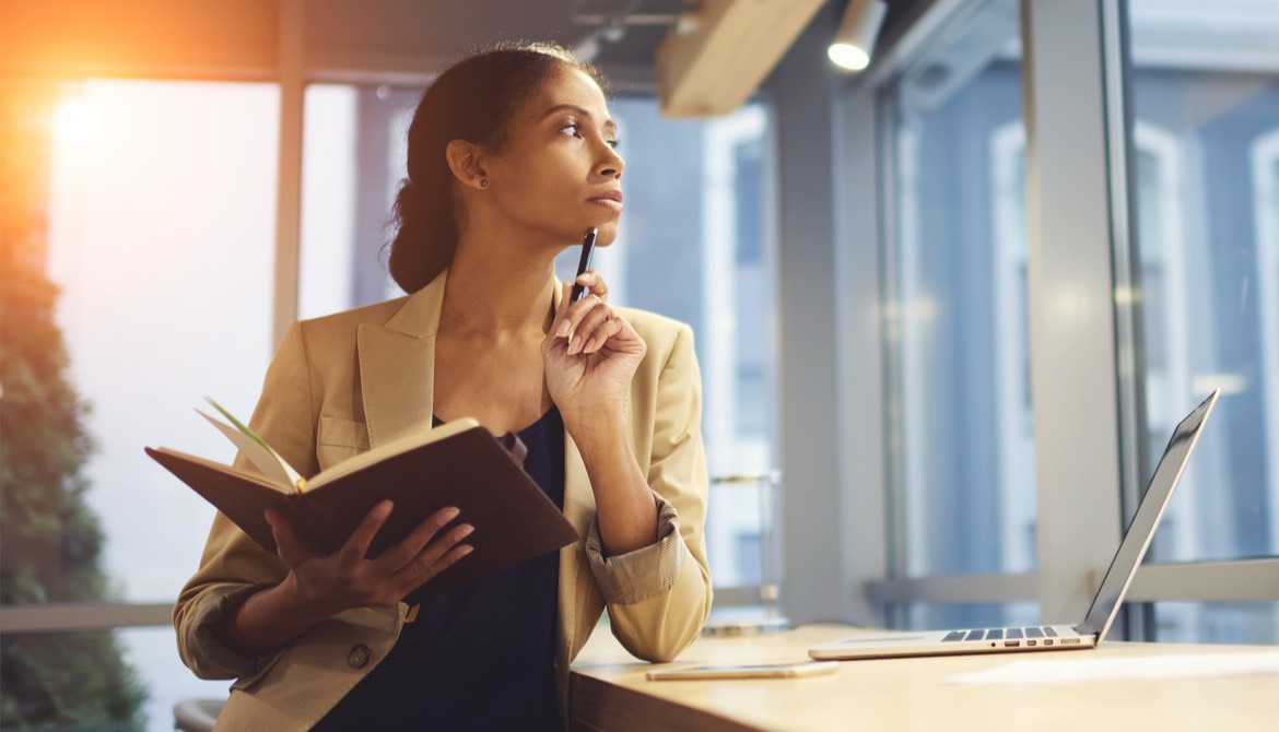 woman staring off thoughtfully into the distance while holding an open book