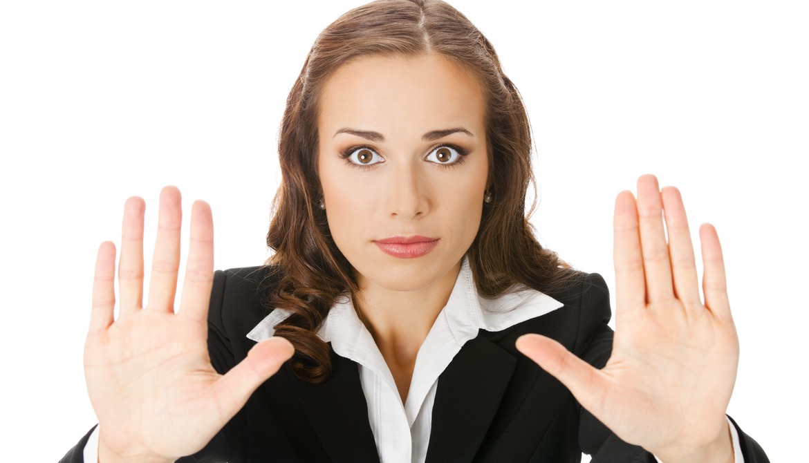 Serious young woman with hands up in stop gesture