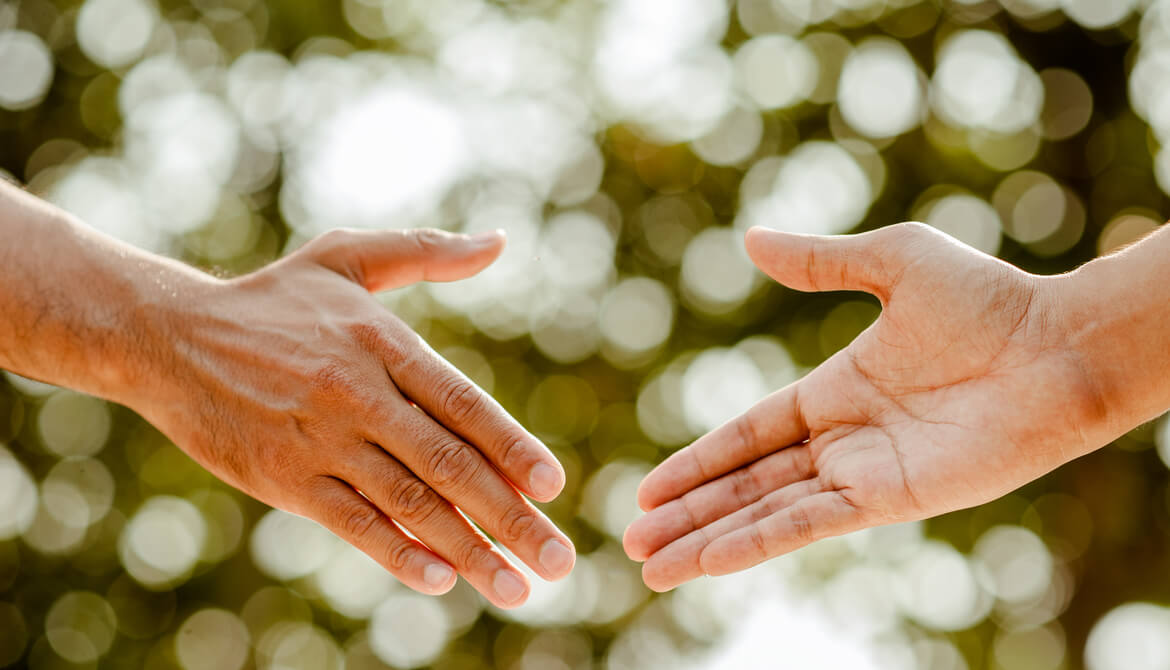 hand held out in gesture of trust and assistance while another hand reaches out to take it