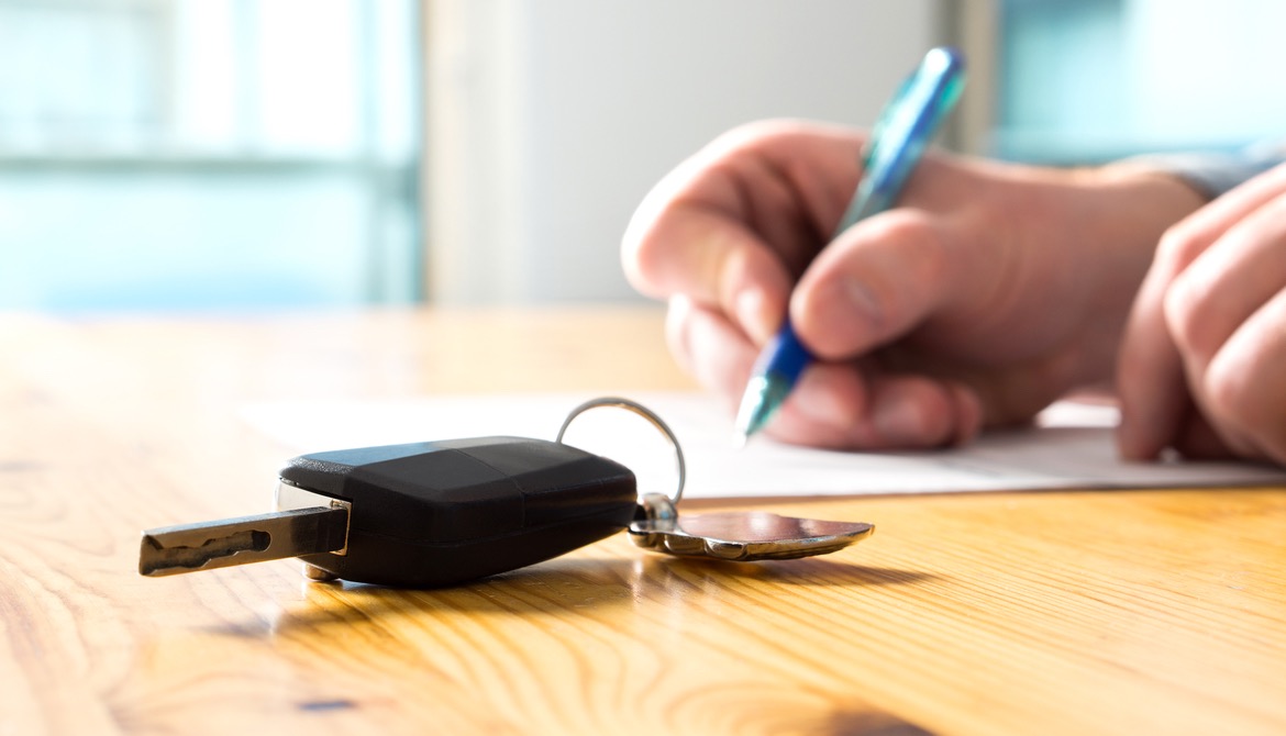 member signing contract for auto loan with car keys laying on table