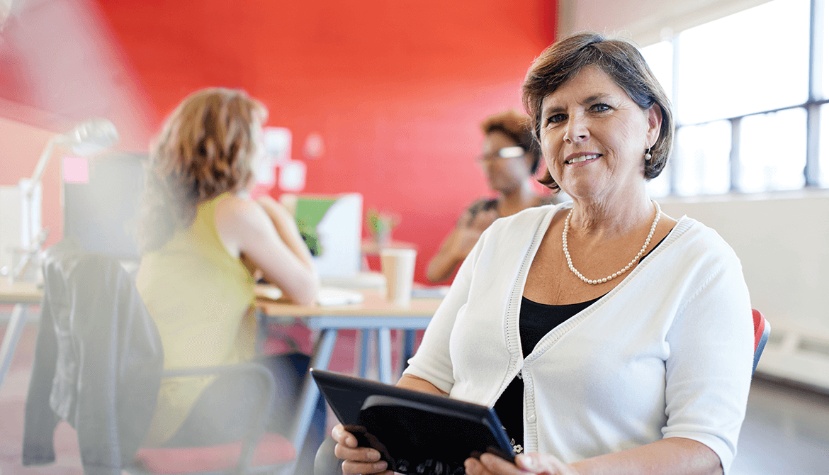 smiling woman wearing pearls using tablet