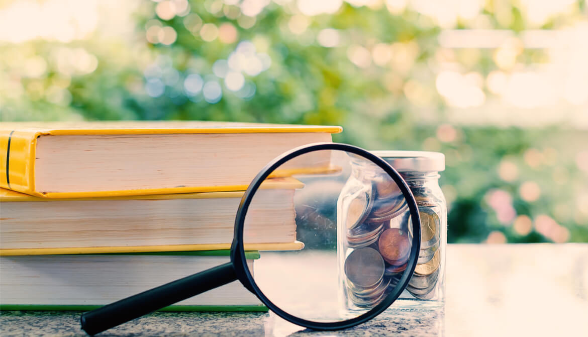 books with nearby money zoomed by a magnifying glass