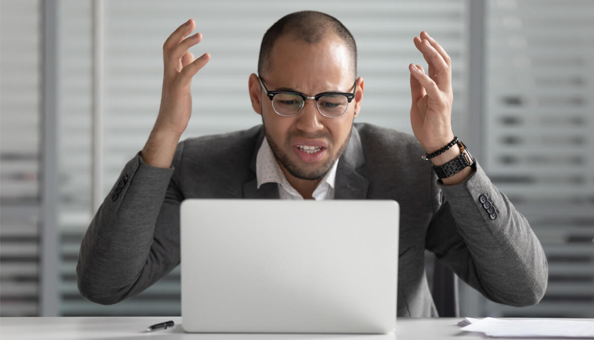 stressed businessman gestures angrily at laptop screen