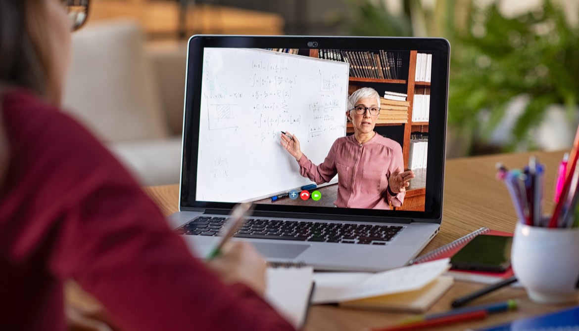 student learning online from teacher shown on laptop screen