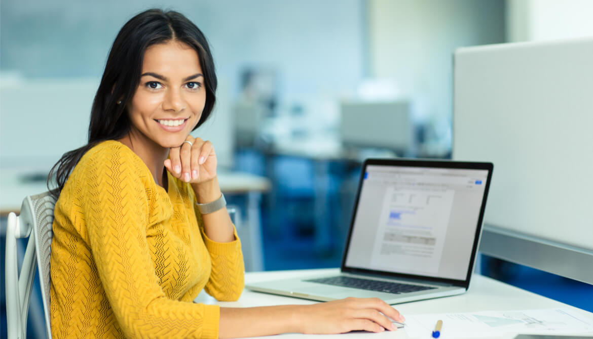 smiling female lending officer in yellow sweater with laptop