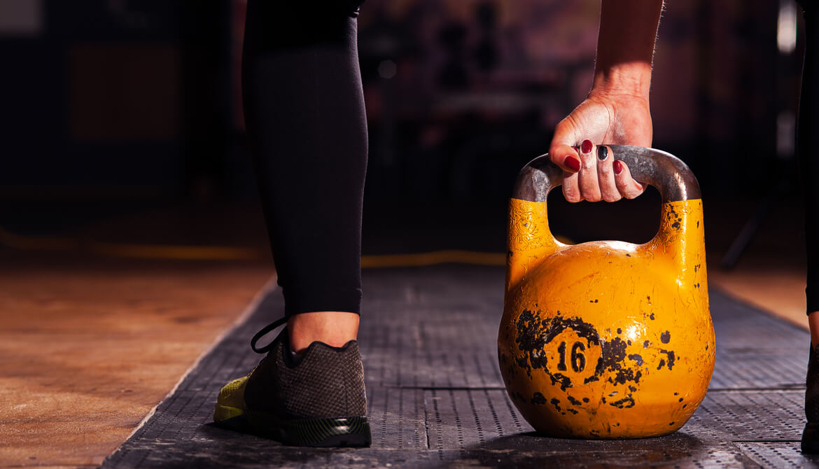 athlete exercising with a yellow kettlebell