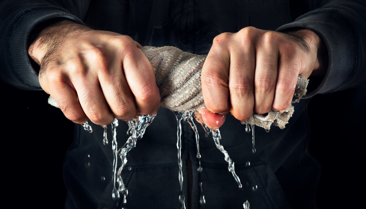 man wrings excess liquid out of a rag