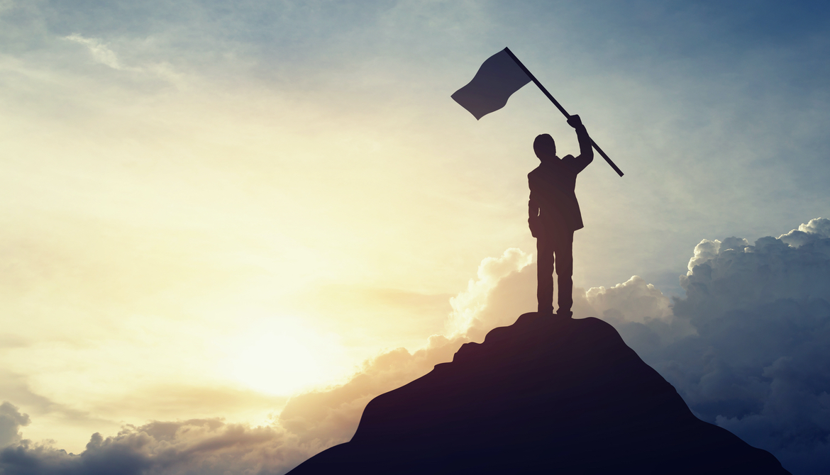 Silhouette of businessman hold a flag on top mountain sky and sun light background