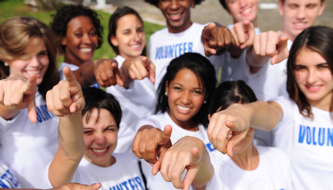 diverse volunteers in white volunteer shirts pointing