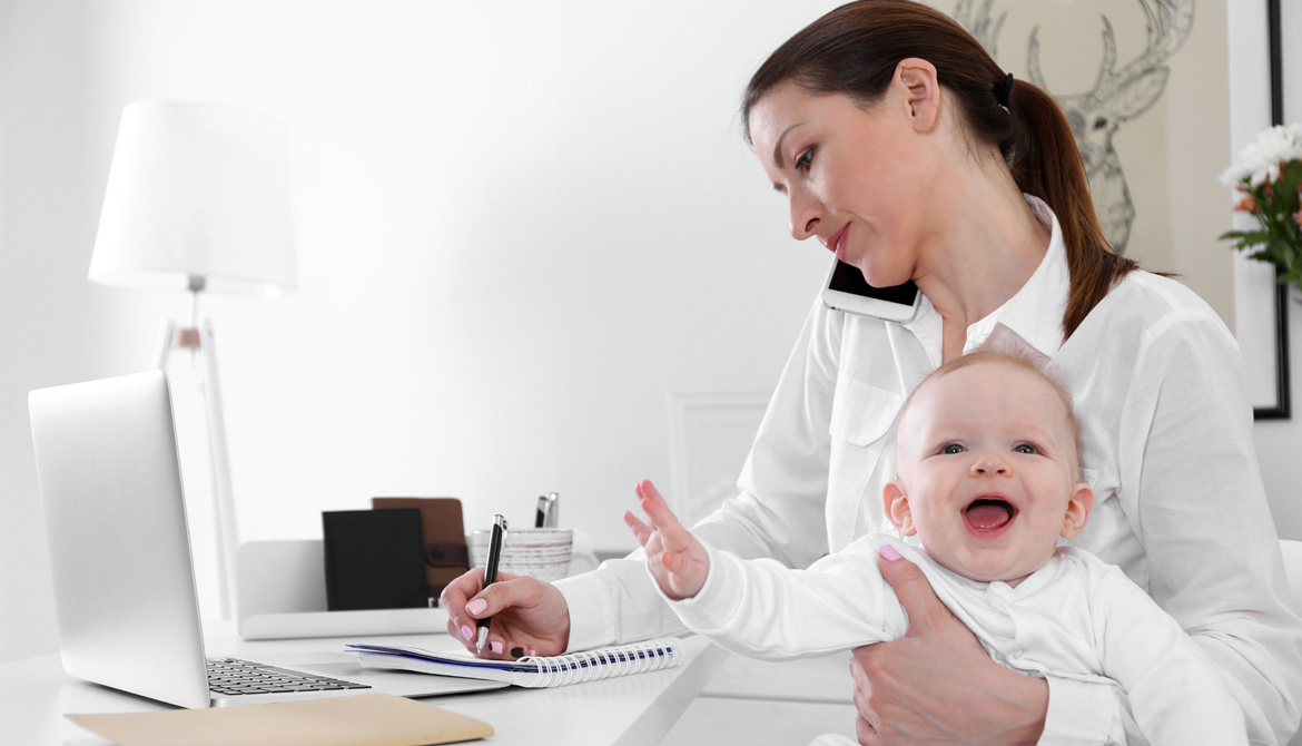 professional mom working from home while holding laughing baby