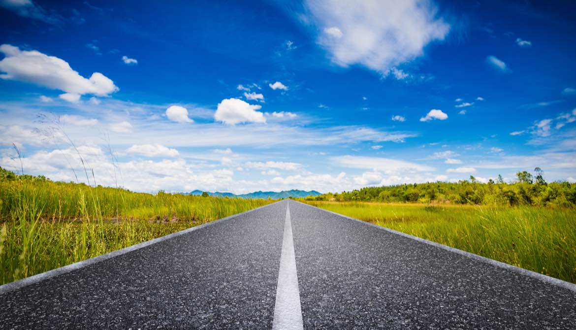 long straight road leading to blue sky