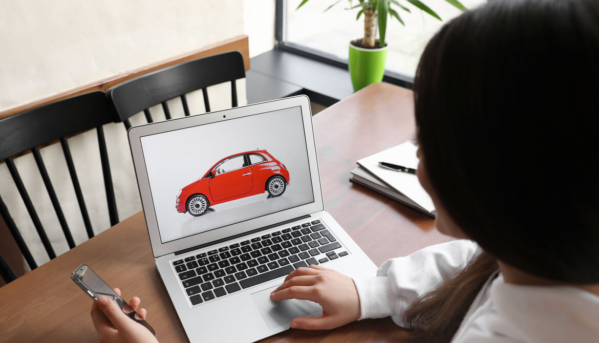 woman using a laptop and a phone to do car shopping