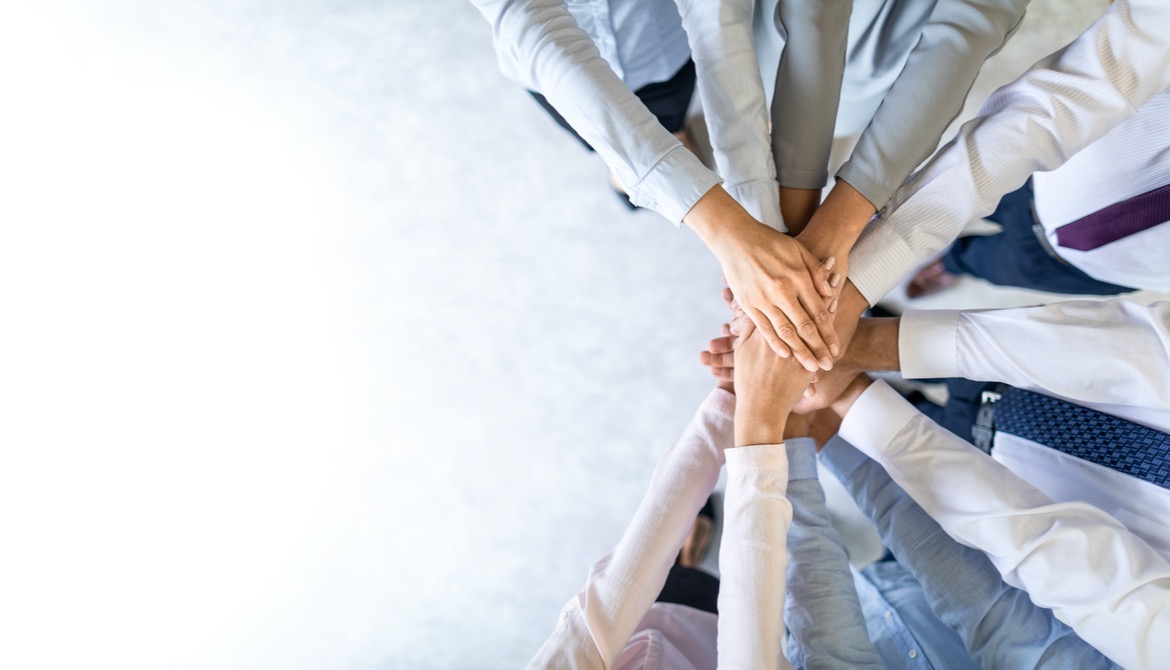 group of employees with all hands in to help each other