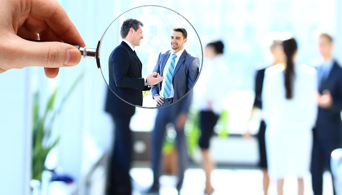 magnifying glass brings potential executive candidates into focus in the midst of a blurry view of a group of businesspeople