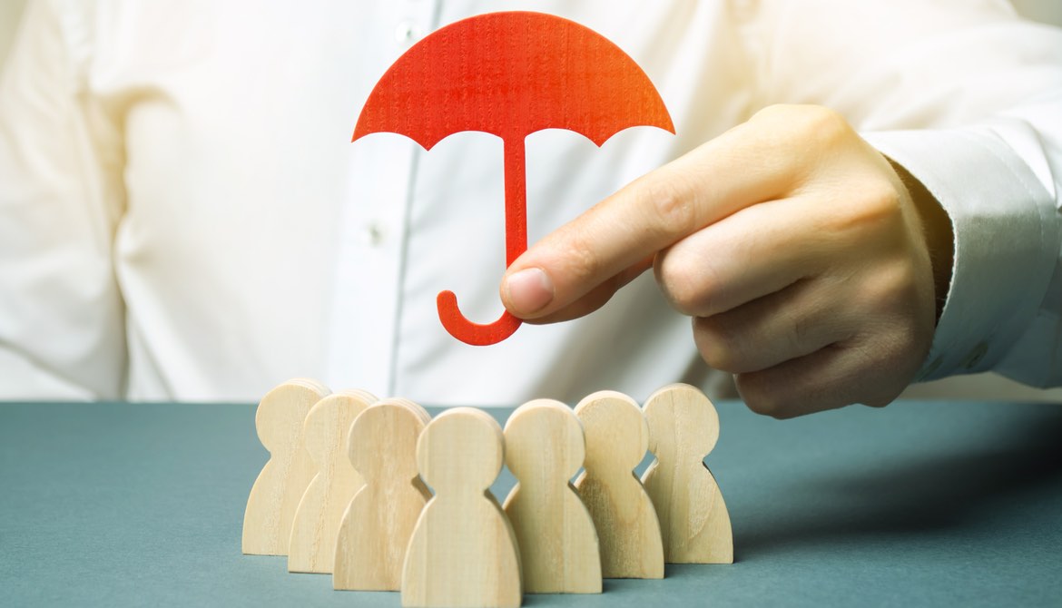 executive holding red paper umbrella over people blocks representing his team