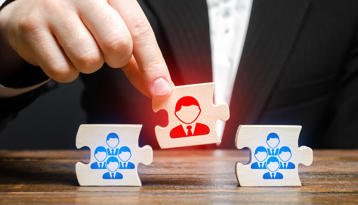 businessperson placing a red puzzle piece representing a leader between blue puzzle pieces representing employee team