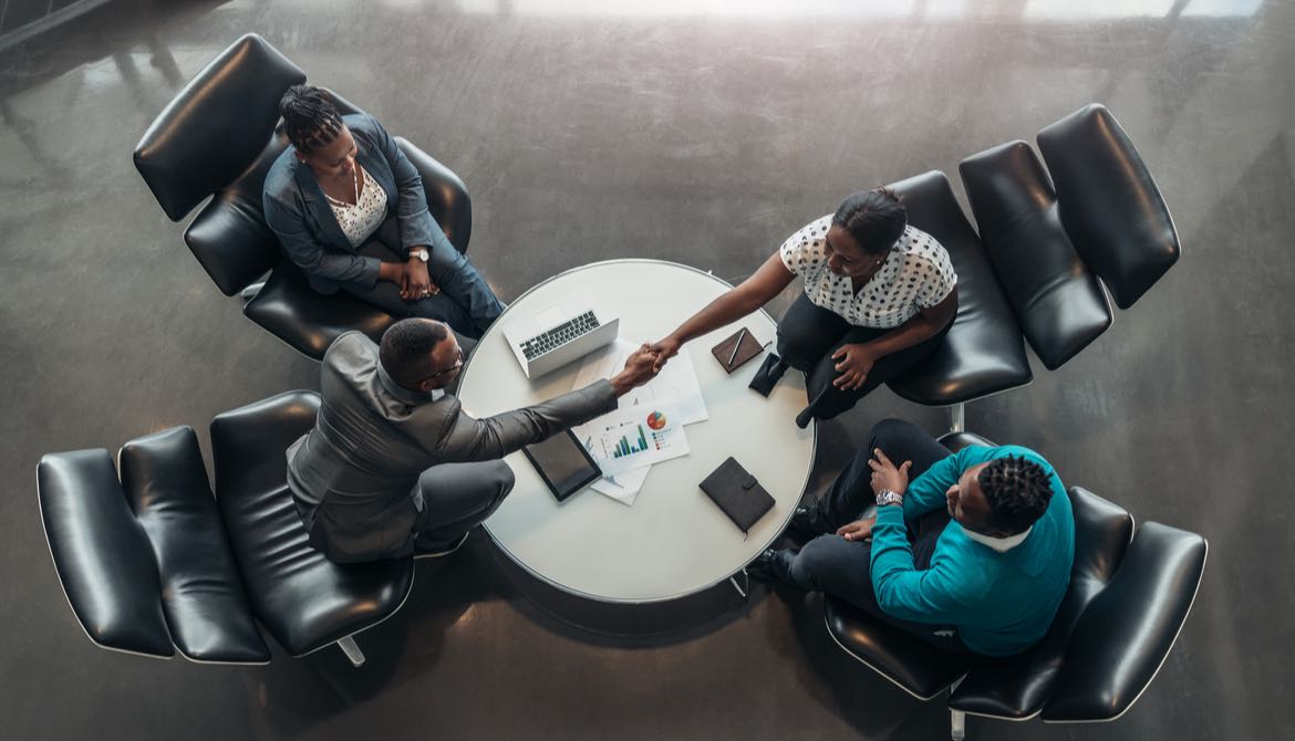 committee of black people having a handshake over a table