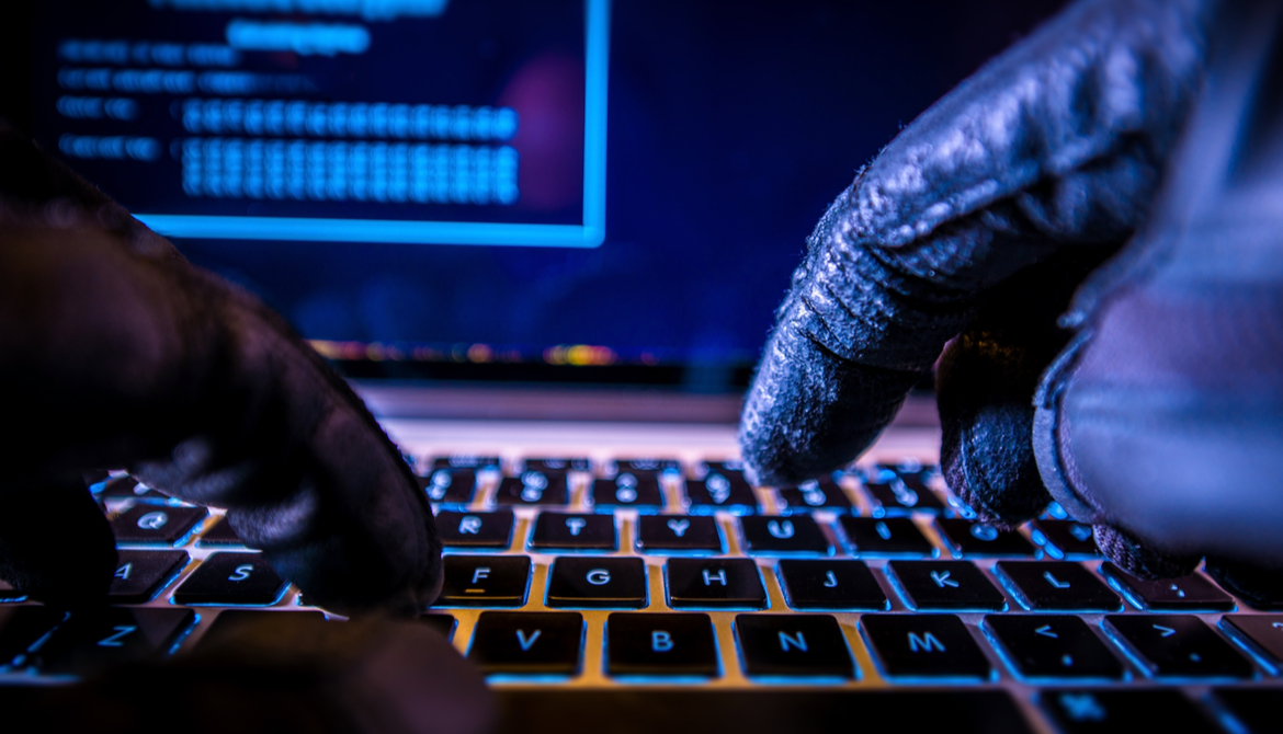 gloved hacker hands with keyboard and screen