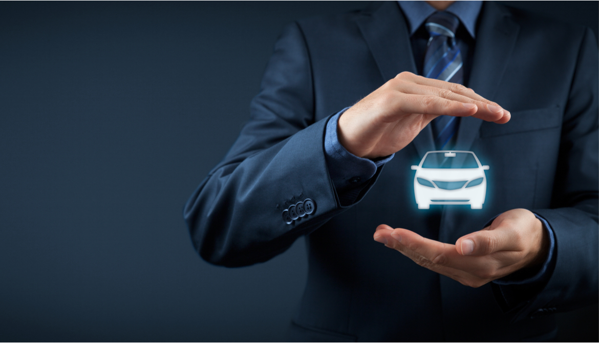 businessman holds and protects small car in his hands