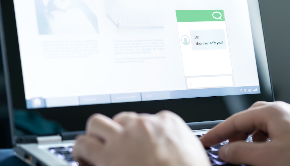 hands typing on laptop that displays chat box where agent asks how they can help