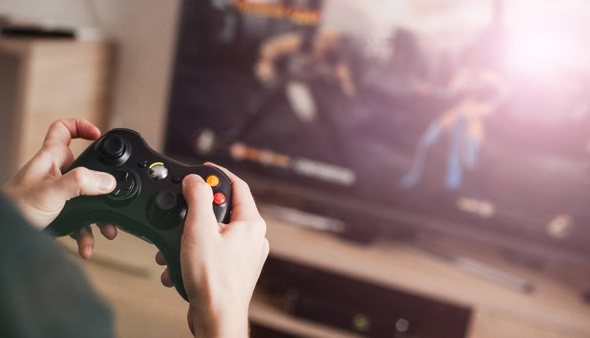 man holding video game controller with fighting game in background