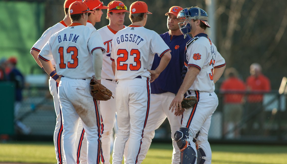 Baseball team infielders meet with coach on the pitcher’s mound