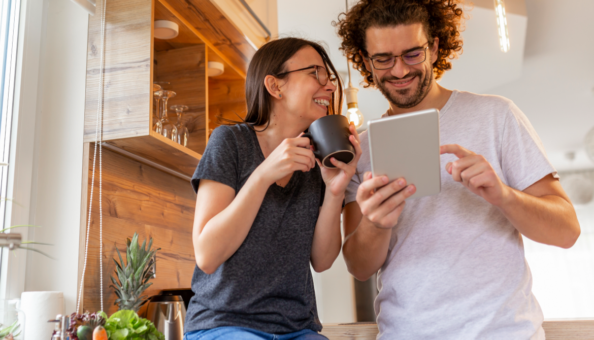 2 individuals laughing looking at a tablet
