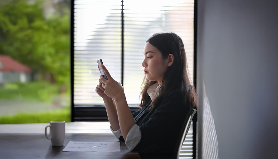 woman sitting at a table looking at her cell phone