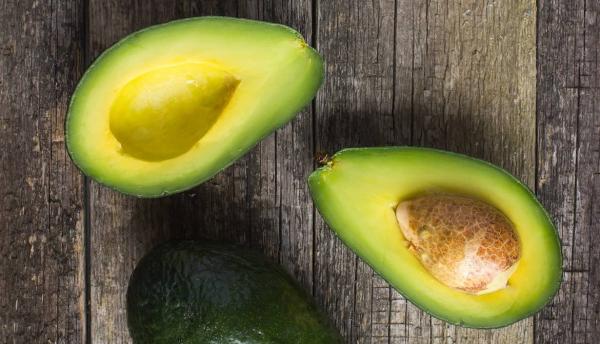 sliced avocados with pit intact on a wooden background