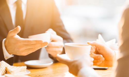 two business people meeting over coffee and panini