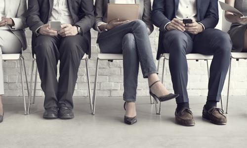 Five job candidates waiting on chairs without faces showing to know their age and race