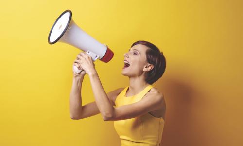 woman in a yellow dress using a bullhorn or megaphone