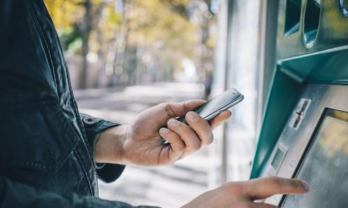 man using his phone to interact with ATM