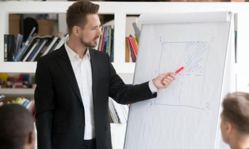 man stands at a flipboard in a meeting