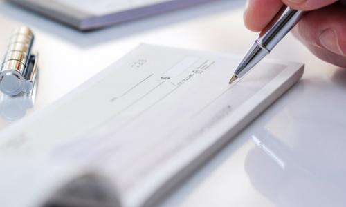 person writing a check with a silver pen