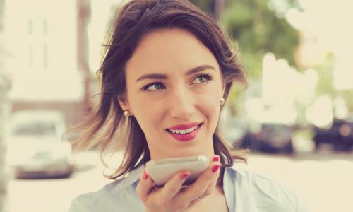 woman using voice assistant on smartphone outdoors